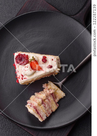 Piece of sweet layer cake with white cream, raspberries and strawberries 122287139