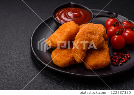 Delicious fresh crispy chicken nuggets on a dark concrete background Delicious fresh crispy chicken nuggets on a dark concrete background 122287320