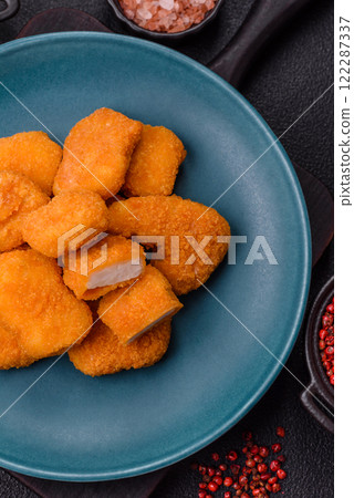 Delicious fresh crispy chicken nuggets on a dark concrete background Delicious fresh crispy chicken nuggets on a dark concrete background 122287337