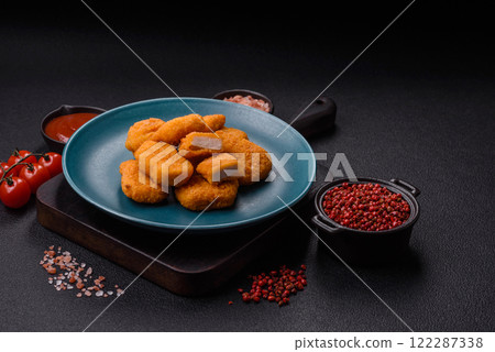 Delicious fresh crispy chicken nuggets on a dark concrete background Delicious fresh crispy chicken nuggets on a dark concrete background 122287338