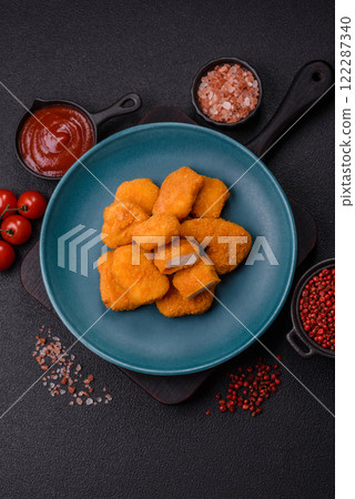 Delicious fresh crispy chicken nuggets on a dark concrete background Delicious fresh crispy chicken nuggets on a dark concrete background 122287340