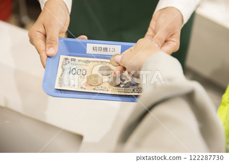 A supermarket clerk receives money in new banknotes 122287730