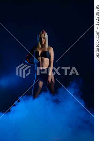 Model posing confidently in a smoky studio with dramatic lighting at night 122288595