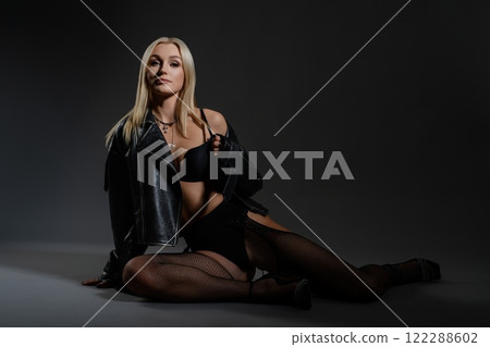 Stylish model poses dramatically in a dark studio setting during a fashion shoot 122288602