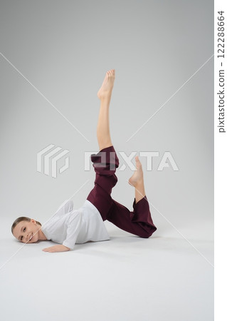 Girl performing an artistic dance pose with grace and precision in a studio Girl performing an artistic dance pose with grace and precision in a studio 122288664