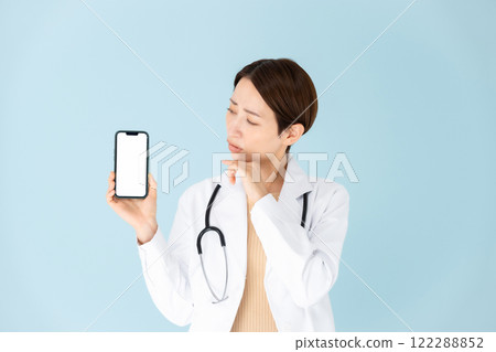 Woman in white coat, stethoscope, smartphone, worries Woman in white coat, stethoscope, smartphone, worries 122288852