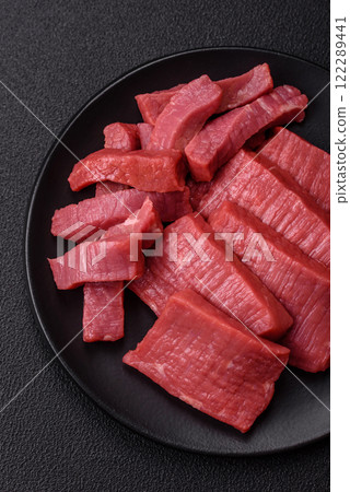Juicy raw beef cut into slices with salt and spices Juicy raw beef cut into slices with salt and spices 122289441