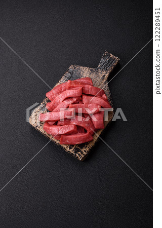 Juicy raw beef cut into slices with salt and spices Juicy raw beef cut into slices with salt and spices 122289451