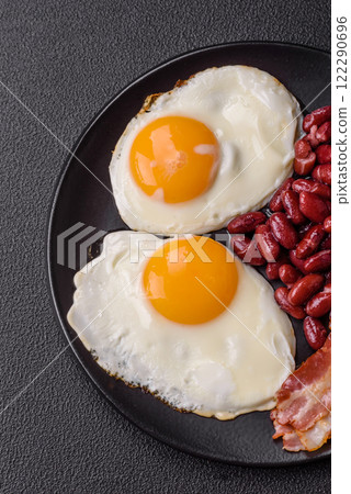 English breakfast with fried eggs, bacon, beans, tomatoes, spices and herbs English breakfast with fried eggs, bacon, beans, tomatoes, spices and herbs 122290696