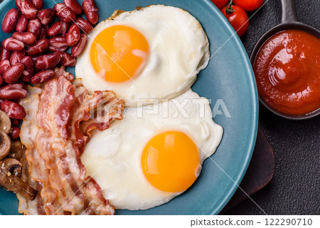 English breakfast with fried eggs, bacon, beans, tomatoes, spices and herbs English breakfast with fried eggs, bacon, beans, tomatoes, spices and herbs 122290710