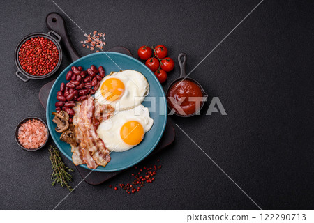 English breakfast with fried eggs, bacon, beans, tomatoes, spices and herbs English breakfast with fried eggs, bacon, beans, tomatoes, spices and herbs 122290713