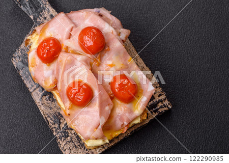 Sandwich with brioche, meat, melted cheese, ham, tomatoes, salt, spices and herbs 122290985