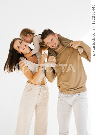 Mother and father are holding a baby on their two year old son. The baby is smiling and the family looks happy 122292443