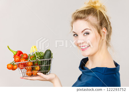 Woman holds shopping basket with vegetables 122293752