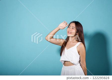 Female raising arm and hand in protection and block sunshine in studio shot isolated on blue background, Asian young woman smile hand up cover face protect sun light and UV, sunscreen cream advertise Female raising arm and hand in protection and block sunshine in studio shot isolated on blue background, Asian young woman smile hand up cover face protect sun light and UV, sunscreen cream advertise 122293828