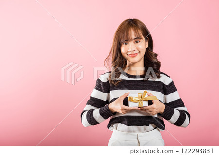 Portrait of happy beautiful Asian young woman smiling holding small gift box on hands, studio shot isolated on pink background, gift for you. Birthday, New year, Christmas, valentine day concept Portrait of happy beautiful Asian young woman smiling holding small gift box on hands, studio shot isolated on pink background, gift for you. Birthday, New year, Christmas, valentine day concept 122293831
