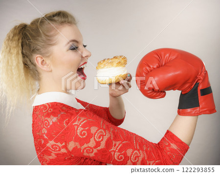 Woman fighting off bad food, boxing cream puff cake Woman fighting off bad food, boxing cream puff cake 122293855