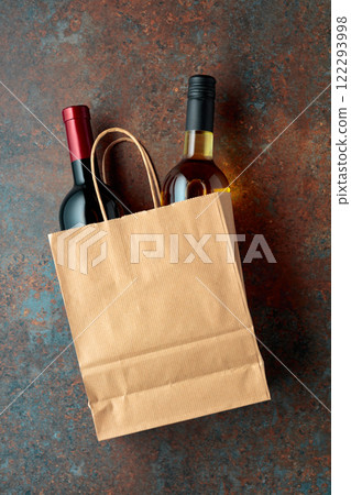 Bottles of red and white wine in a paper bag on a rusty background. 122293998