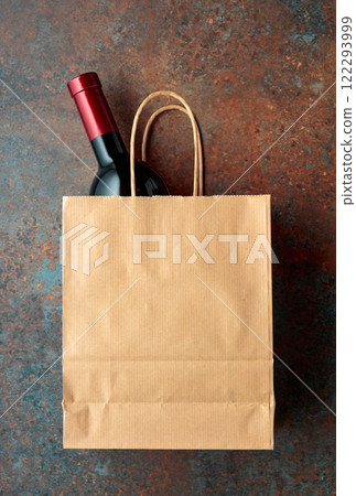Bottle of red wine in a paper bag on a rusty background. 122293999