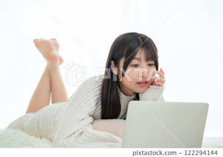 A Japanese woman lying face down and operating a computer 122294144