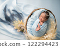 Newborn photo_A newborn baby sleeping peacefully with a happy smile wrapped in a swaddling cloth 122294423