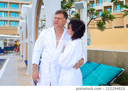 Mature couple in white robes relaxing by the pool 122294628