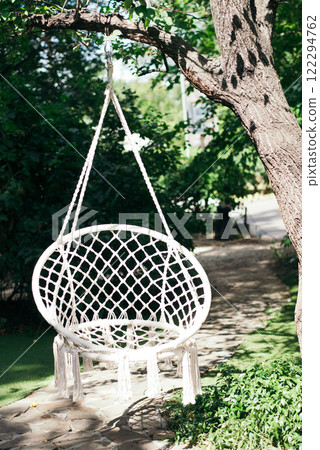 White macrame swing hanging in the garden. Summer outdoor garden background 122294762