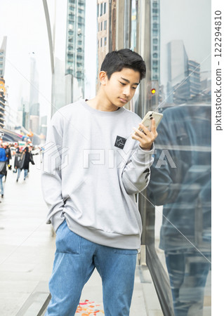 A boy looking at his smartphone in the street 122294810