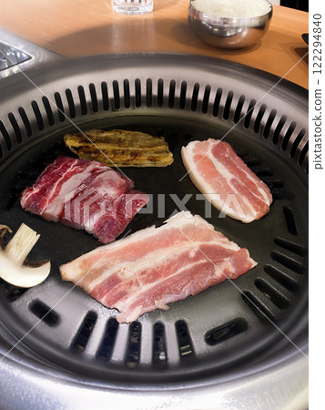 Korean barbecue, roasting mix of meat, pork, beef over a fire in the middle of the table. Korean style. Vertical photo Korean barbecue, roasting mix of meat, pork, beef over a fire in the middle of the table. Korean style. Vertical photo 122294840