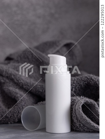White blank pump cream bottle near dark grey bath towel closeup, cosmetic mockup White blank pump cream bottle near dark grey bath towel closeup, cosmetic mockup 122295013