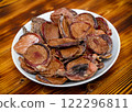 Dried beef testicles for pet feeding. Plate with food on wooden table. 122296811