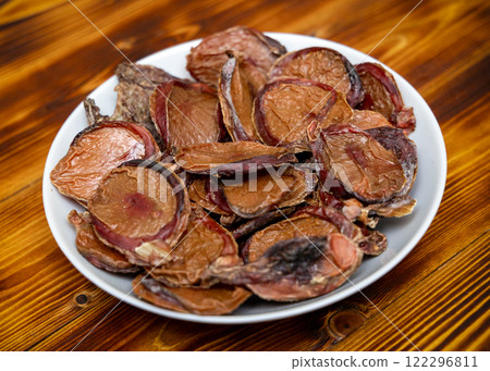 Dried beef testicles for pet feeding. Plate with food on wooden table. Dried beef testicles for pet feeding. Plate with food on wooden table. 122296811