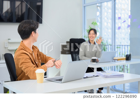 Two cheerful colleagues having lighthearted conversation in a modern office 122296890