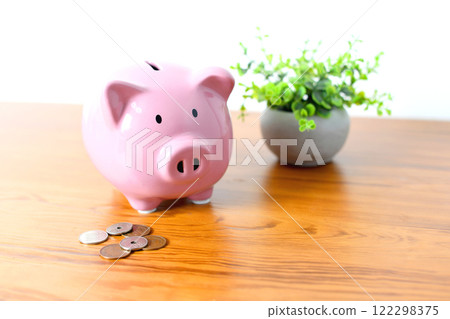 Image of a piggy bank and coins on a desk Image of a piggy bank and coins on a desk 122298375