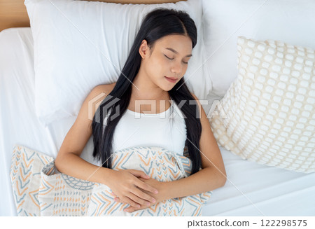Top view beautiful Asian woman lie and sleep on bed with white pillow and turn head to her left side and look relax happiness. 122298575