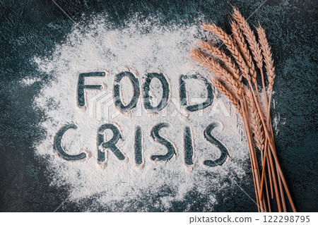 The inscription FOOD CRISIS on flour next to wheat. Dark background The inscription FOOD CRISIS on flour next to wheat. Dark background 122298795