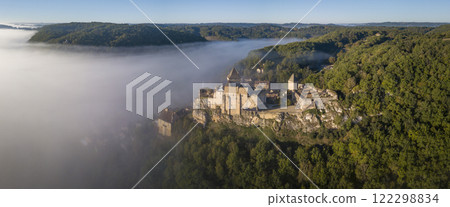 Majestic chateau de Castelnaud rises above misty Dordogne valley during sunrise, revealing its 122298834