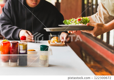 Waitress serving healthy green vegetable salad with bread bun in the morning. Waitress serving healthy green vegetable salad with bread bun in the morning. 122300672