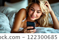 A girl in bed with a phone is chatting pleasantly 122300685