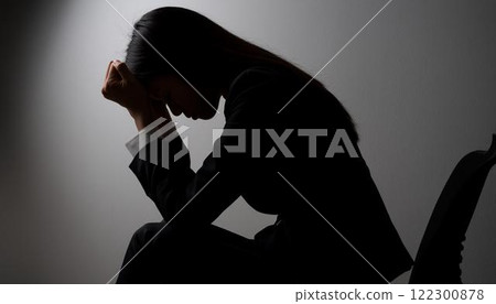 Silhouette of a woman hugging her knees in the dark 2 122300878