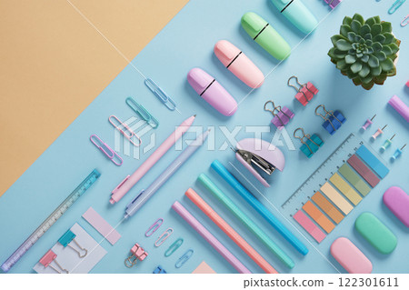 Stationery with markers, felt-tip pens, paper clips, erasers, stapler, pastel-colored stickers neatly arranged on a light blue and beige background. Space for text. Stationery with markers, felt-tip pens, paper clips, erasers, stapler, pastel-colored stickers neatly arranged on a light blue and beige background. Space for text. 122301611