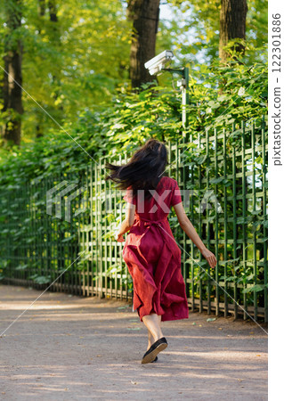 View from back, young African American woman in burgundy maxi dress, adorable female model posing View from back, young African American woman in burgundy maxi dress, adorable female model posing 122301886