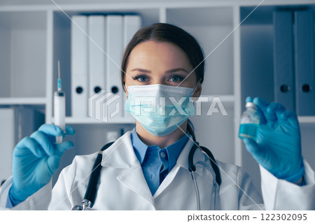 In a wellorganized lab, a health professional holds a syringe and vial, highlighting their vital role in healthcare and commitment to patient safety through proper medical techniques and protocols 122302095