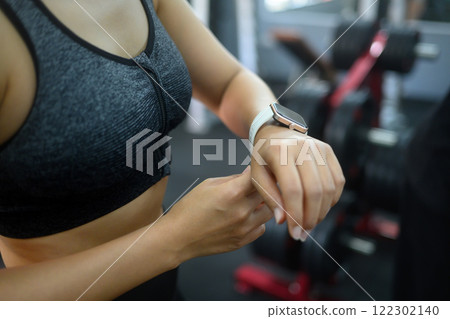Close up of female athlete checking her smartwatch during a workout in the gym 122302140