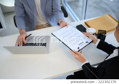 Job candidate handing over her resume during job interview Job candidate handing over her resume during job interview 122302170