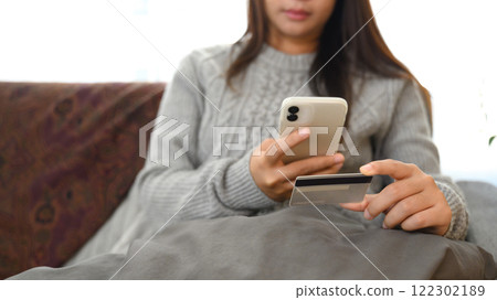 Young woman using mobile phone and credit card. Mobile payments and digital transactions concept 122302189