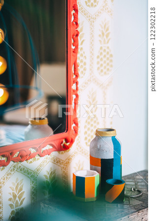 iron box on wooden legs with red frame on the wall and lamp. photo zone with mirror and table 122302218