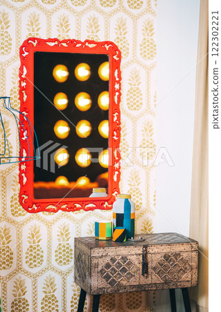 iron box on wooden legs with red frame on the wall and lamp. photo zone with mirror and table iron box on wooden legs with red frame on the wall and lamp. photo zone with mirror and table 122302221