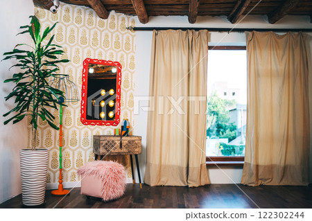 iron box on wooden legs with red frame on the wall and lamp. photo zone with mirror and table 122302244