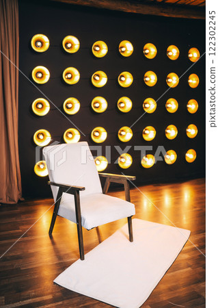 armchair with light fabric against of incandescent lamps. area with armchair and bright floor lamps armchair with light fabric against of incandescent lamps. area with armchair and bright floor lamps 122302245